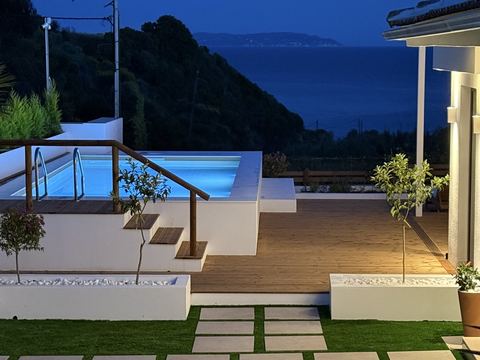 Πισίνα με φωτισμό και θέα στη θάλασσα το σούρουπο