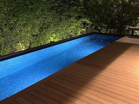Πισίνα με μπλε liner και ξύλινο deck τη νύχτα
